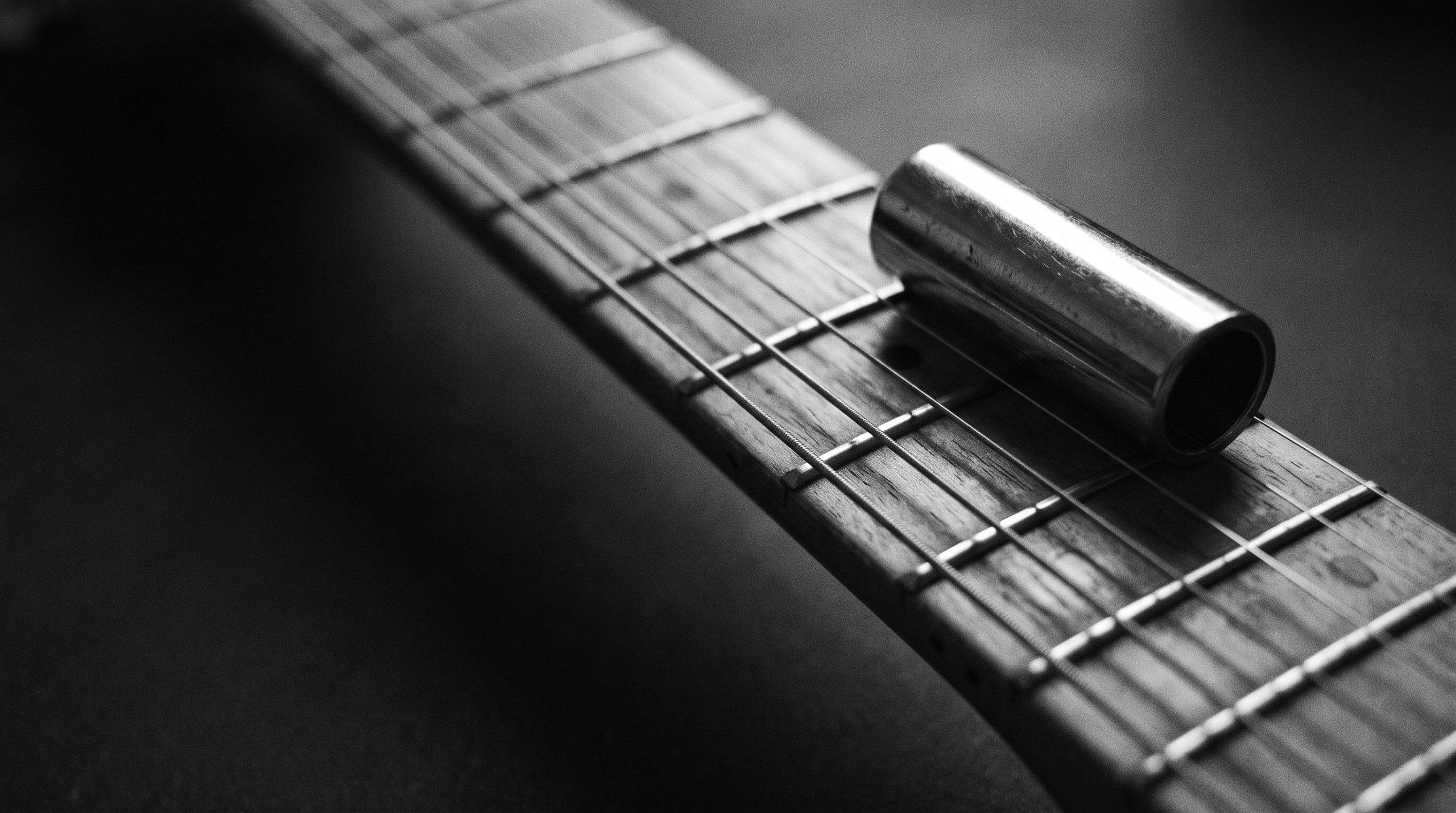 Chrome slide resting across the strings of an electric guitar neck, played in standard tuning without open G
